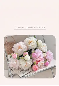 Vue détaillée d'un bouquet de pivoines artificielles rose et crème sur une chaise blanche