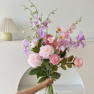 Close-up of artificial bouquet with pink peonies and purple irises held by hand