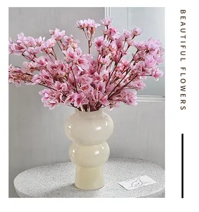 Flores de durazno artificiales rosadas en un jarrón moderno para decoración
