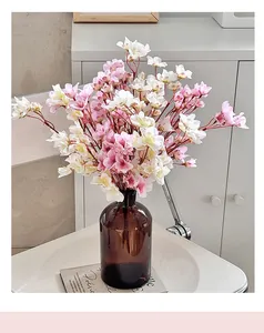 Primer plano de flores de cerezo artificiales en un jarrón de cristal marrón