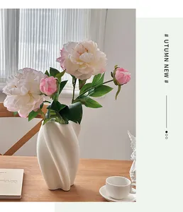 Gros plan de pivoines artificielles roses dans un vase en céramique spirale sur bois