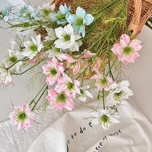 Künstliche Schwarzkümmel-Blumen in Rosa, Weiß und Blau in einem geflochtenen Korb