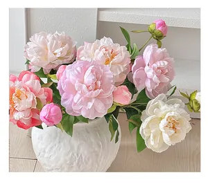Gros plan d'un bouquet de pivoines artificielles roses et blanches dans un vase texturé