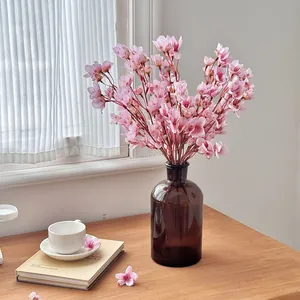 Ramas de cerezo artificiales rosas en un jarrón de vidrio marrón para decorar