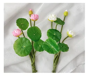 Detail of faux lotus flowers and green leaves on a white linen fabric background