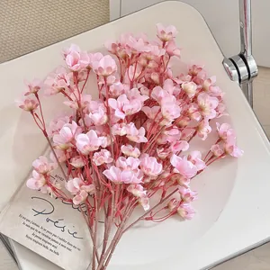 Flores de cerezo de seda rosa realistas en silla blanca para decorar el hogar