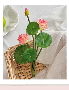 Detail of lifelike pink artificial lotus bouquet with green leaves in a woven basket