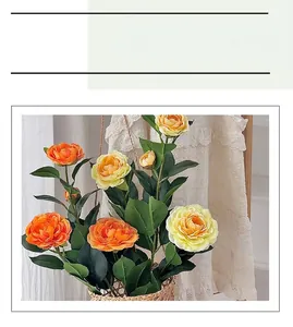 Dettaglio di fiori di camelia artificiali arancioni e gialli in un cestino di vimini