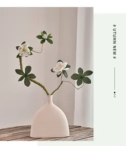 Détail de fleurs d'azalée blanches au crochet dans un vase en céramique sur bois