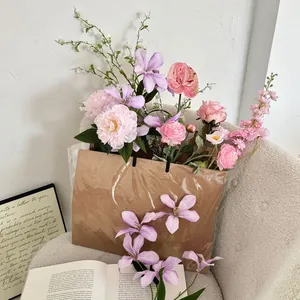 Close-up of artificial flower bouquet with pink peonies in a brown kraft paper gift bag