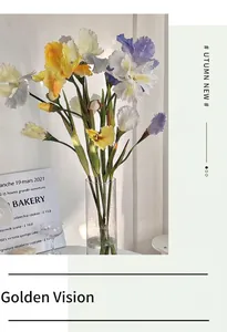 Close-up of realistic artificial iris flowers with detailed petals in a glass vase