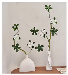 Détail de vases en céramique minimalistes avec branches d'azalées sur table en bois