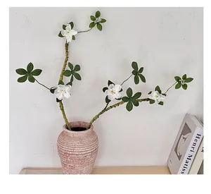 Détail de branches d'azalées blanches artificielles texturées dans un vase en céramique