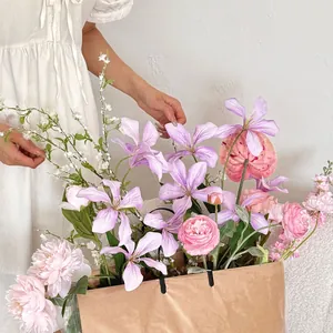Artistic bouquet of faux peonies and dahlias in a brown paper bag with model