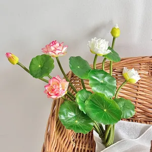 Artificial lotus flowers in gradient pink and white colors with green leaves in a basket