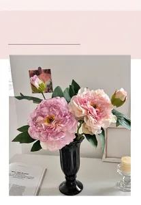 Detail of pink artificial peony flowers in a black wavy ceramic vase for home decor