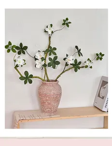 Gros plan détaillé de fleurs d'azalées artificielles blanches dans un vase en céramique texturé