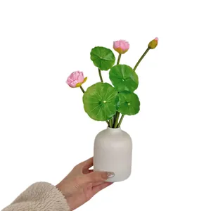 Artificial pink lotus flowers with green leaves in a white ceramic vase for home decor