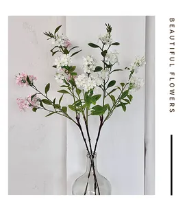 Close-up of white and pink artificial freesia with realistic green leaves in a glass vase