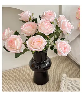 Close-up of pink artificial roses in a black matte vase on a modern minimalist rug