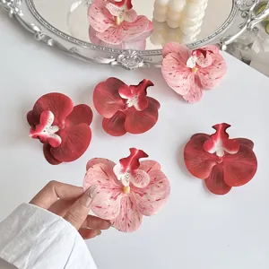 Kunstmatige orchideeënbloemhoofdjes in donkerrood en roze op vintage dienblad voor DIY
