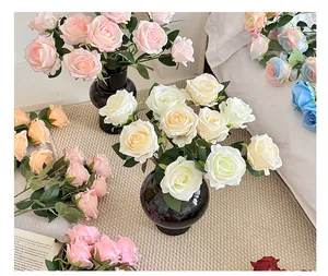 Flat lay of artificial silk roses in multiple colors arranged with a vase and book