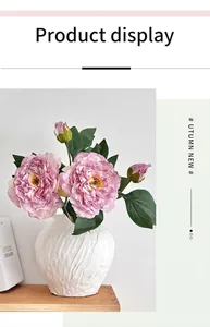 Close-up of pink peony silk flowers with two buds in a white textured ceramic vase