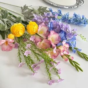Detail of faux bouquet with yellow buttercup, blue delphinium and freesia on white background