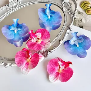 Artistieke opstelling van blauwe en roze orchideekoppen met zijden textuur op een spiegel
