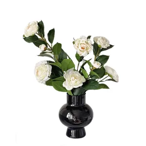 Künstliches weißes Kamelien-Arrangement in einer glänzenden schwarzen Keramikvase
