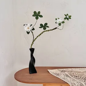 Branche de fleurs blanches artificielles dans un vase moderne noir en spirale décoratif