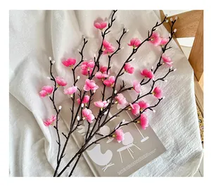 Detalle de una rama de ciruelo artificial rosa sobre un fondo de tela de algodón blanco