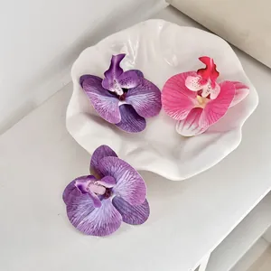 Detailopname van zijden orchideebloemen in paars en roze op een witte keramische schaal