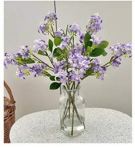 Détail de fleurs artificielles violettes dans un vase sur une table minimaliste