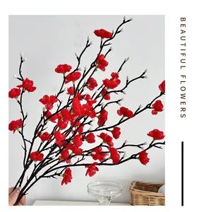 Detalle de ramas de ciruelo artificiales rojas con flores de seda y tallos de plástico marrón