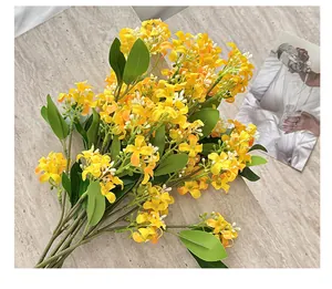 Détail de fleurs d'osmanthus jaunes artificielles avec feuilles sur surface en marbre