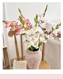 Dettaglio di gladioli artificiali in un vaso di ceramica rosa con texture