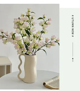 Vaso moderno in ceramica color crema con manico a S ondulato e fiori decorativi finti