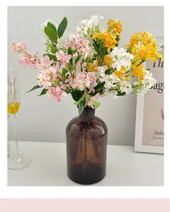Vue détaillée de fleurs artificielles roses et jaunes dans un vase en verre brun