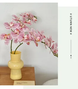 Close-up of pink artificial orchids in a yellow textured glass vase for home decor