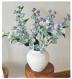 Campanule blu artificiali in un vaso bianco testurizzato su uno sgabello di legno