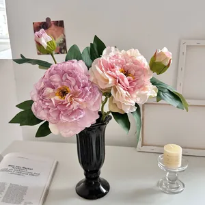 Elegant kunstmatig pioenrozenarrangement met roze bloemen in een zwarte vintage vaas decor