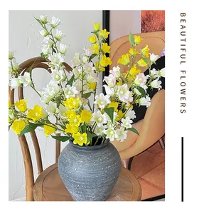 Primo piano di campanule artificiali bianche e gialle in un vaso di ceramica grigio