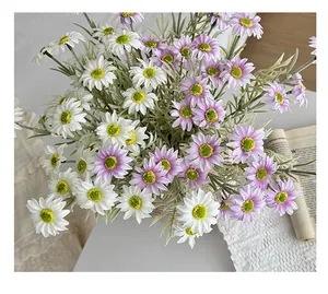 Close-up of white and purple artificial daisy silk flowers on a textured white cloth