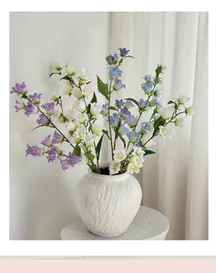 Dettaglio di fiori di mughetto artificiali viola e bianchi in un vaso di ceramica