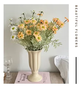Detail view of artificial white and orange daisy set in a wave-top ceramic vase