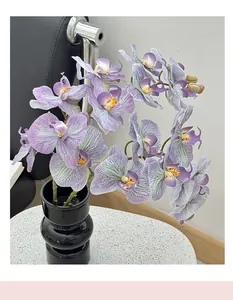 Macro view of purple faux orchid petals and a layered black ceramic vase on a white table