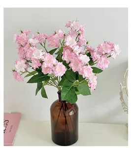 Detail of pink artificial cherry blossom in a dark brown glass vase for home decor
