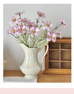Detail einer Vintage-Keramikvase mit geprägten Blütenblättern und künstlichen Kosmosblumen
