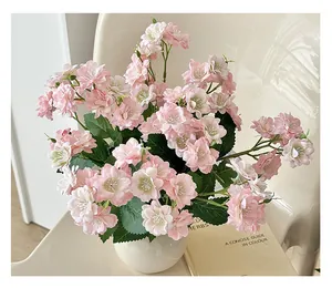 Detail of pink artificial jasmine flowers in white ceramic vase on cream chair